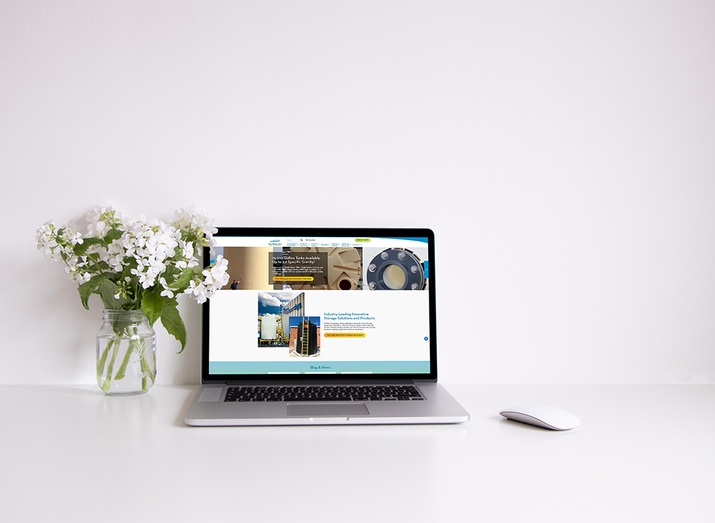 A modern laptop displaying a website on a clean desk next to a vase of white flowers, illustrating a professional workspace setup for productivity and creativity.