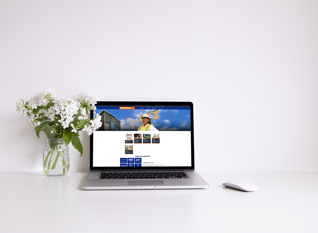 Laptop displaying a construction company website on a clean desk with a vase of white flowers, emphasizing a professional and modern workspace.